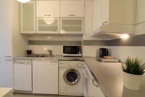 cocina blanca con lavadora y microondas en Stay Nexus Galaxy Center en Sofía