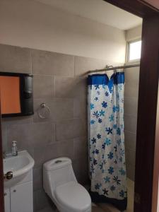 y baño con aseo y cortina de ducha. en Departamento amueblado moderno, en Manta