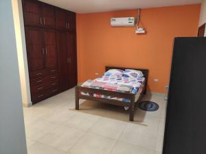 1 dormitorio con cama y pared de color naranja en Departamento amueblado moderno, en Manta