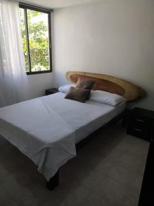 a bedroom with a large bed with white sheets and a window at Hermoso apto a una cuadra de la playa rodadero in Gaira