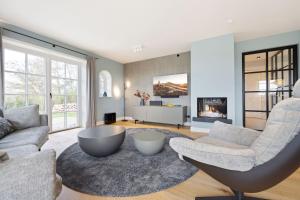 ein Wohnzimmer mit Sofa und Stühlen und einem Kamin in der Unterkunft Haus Süderjen in Westerland