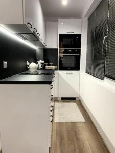 eine Küche mit weißen und schwarzen Arbeitsflächen und Geräten in der Unterkunft Asitad DeLuxe Apartments in Ruse