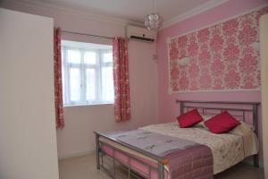 een slaapkamer met roze muren en een bed met rode kussens bij Apsara Villas in Flic-en-Flac
