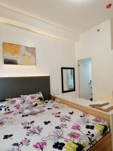 a bedroom with a bed with a floral bedspread at Modena Town Square-Walkup Condominium in Minglanilla