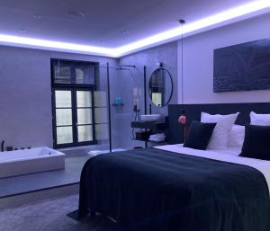 1 dormitorio con 1 cama grande y bañera en Ennéa - Jacuzzi & Luxury Suites, en Perpiñán