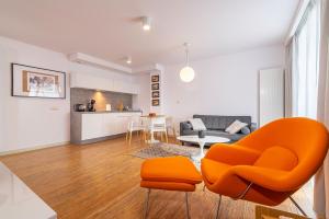 a living room with an orange chair and a couch at Apartament DREAM in Pogorzelica