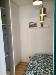um quarto com uma cama e uma parede branca em Appartement avec terrasse et parking gratuit accolé em Montbéliard