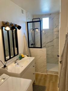 La salle de bains est pourvue d'un lavabo blanc et d'une douche. dans l'établissement Appartement avec terrasse et parking gratuit accolé, à Montbéliard