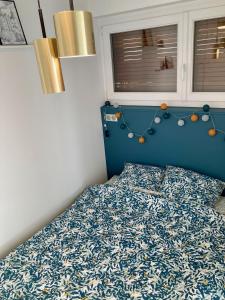 um quarto com uma cama com uma cabeceira azul em Appartement avec terrasse et parking gratuit accolé em Montbéliard