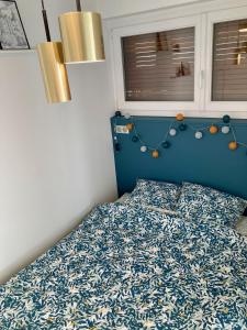 Schlafzimmer mit einem Bett mit blauem Kopfteil in der Unterkunft Appartement avec terrasse et parking gratuit accolé in Montbéliard