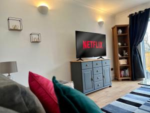 a living room with a television on top of a dresser at Family & pet friendly house + private garden in Oakhill