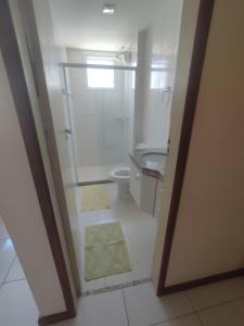 a white bathroom with a toilet and a sink at Seu Apê na Enseada Azul - Bacutia !!! in Guarapari