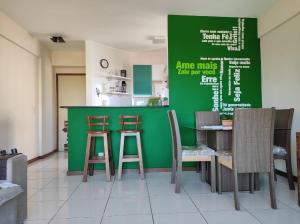 a restaurant with a green wall with chairs and a table at Seu Apê na Enseada Azul - Bacutia !!! in Guarapari