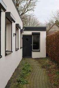 una casa con una puerta negra y una pasarela en B & B De Rode Beuk, en Hilvarenbeek