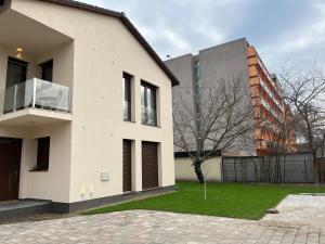 a white house with a tree and a building at Nature in the City upper storey Bestern in Szeged