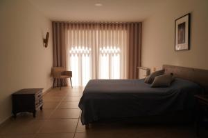 um quarto com uma cama e uma janela com cortinas em Quinta do Areal em Lousã