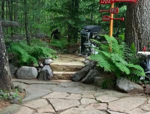 a garden with a stone walkway in a forest at The croquet cabin your year round romantic escape in Boulder Junction