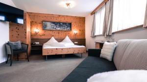 a bedroom with a bed and a desk and a couch at Hotel Alpina in Ischgl