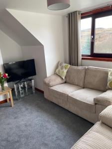 a living room with a couch and a tv at Almondbank Self Catering Apartment in Skeabost