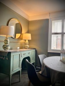 a room with a table with a lamp and a mirror at Historic & Stylish Cottage in Charlton Kings
