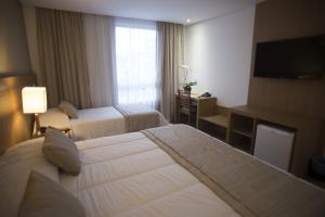 a hotel room with two beds and a television at Casablanca Center Hotel in Petrópolis