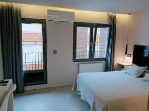 a bedroom with a white bed and two windows at Ardigales 11 in Castro-Urdiales
