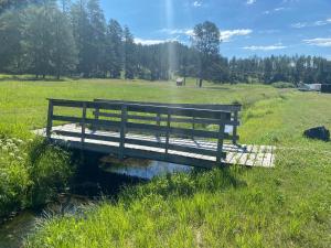 un banco sentado en un puente sobre un arroyo en Cabin 9 at Horse Creek Resort, en Rapid City