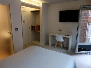 een slaapkamer met een bed, een bureau en een televisie bij Ardigales 11 in Castro-Urdiales