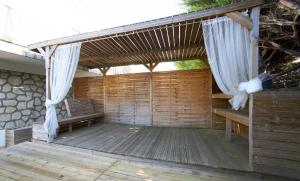 a wooden deck with a bench and curtains on it at Agréable maison en centre ville in Noisy-le-Grand