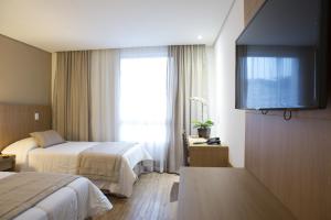 a hotel room with two beds and a flat screen tv at Casablanca Center Hotel in Petrópolis