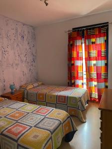 a bedroom with two beds and a window with curtains at Palm mar Relax House in Palm-mar