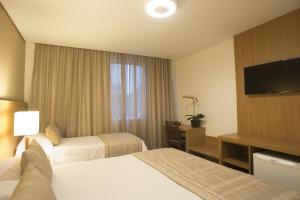 a hotel room with two beds and a flat screen tv at Casablanca Center Hotel in Petrópolis