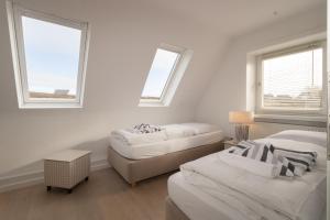 a white room with two beds and two windows at Budersandhaus in Hörnum