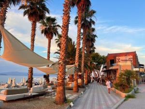 a row of palm trees on a sidewalk next to the beach at Sunrise Luxury House in Pefkochori