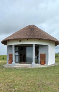 a small hut with a thatched roof in a field at Wild Coast Grosvenor Holiday Home in Lusikisiki