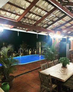 un patio con una piscina con mesa y sillas en Magia da Serra Casa Temporada, en Pirenópolis