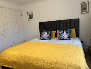 1 dormitorio con 1 cama grande con sábanas y almohadas amarillas en Family & pet friendly house + private garden en Oakhill