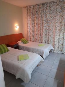 2 Betten in einem Hotelzimmer mit Vorhängen in der Unterkunft Onisillos Hotel in Larnaka