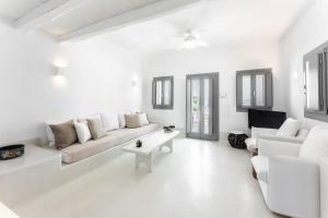 ein weißes Wohnzimmer mit einem Sofa und einem Tisch in der Unterkunft Philosophia Luxury Villa in Megalochori