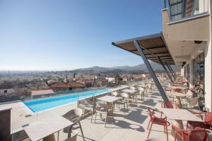 een balkon met tafels en stoelen en een zwembad bij AKROTHEA suites & lounge in Tripolis