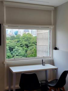 ein Fenster in einem Zimmer mit einem Schreibtisch und Stühlen in der Unterkunft Studio Silvia in São Paulo