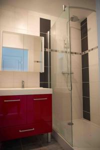 La salle de bains est pourvue d'un lavabo, d'une douche et d'une armoire rouge. dans l'établissement Appart cosy 4/6 personnes idéalement placé, à Aytré