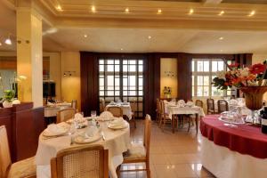 un comedor con mesas y sillas blancas y registradora en Logis Auberge des Vieux Chenes, en Malemort-sur-Corrèze