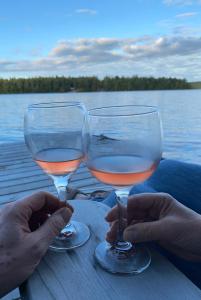 two glasses of wine sitting on a table by the water at Bear Cabin - Cozy Forest Retreat nearby Lake in East Kemptville