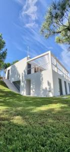 una casa blanca en la cima de un campo de hierba en casas barrio cerrado costa esmeralda en Pinamar