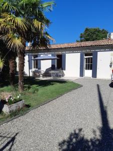 ein weißes Haus mit einer Palme und einer Terrasse in der Unterkunft Bastida in Saint-Macaire