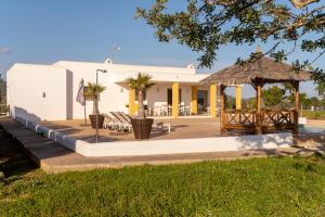 a large white building with a pavilion and palm trees at Villa con piscina Ibiza centro in Sant Josep de sa Talaia