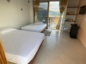 two beds in a room with a large window at Apartamento Rodadero frente a la playa in Rodadero