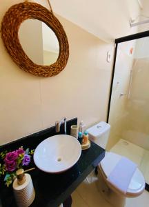 een badkamer met een wastafel, een toilet en een spiegel bij Casa - villa luisa a 100m do mar in Paripueira