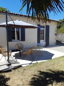 eine Terrasse mit einem Tisch, Stühlen und einem Sonnenschirm in der Unterkunft Bastida in Saint-Macaire